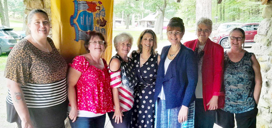 Sussex County Aglow leadership team and Elaine Santo, in front of the New Jersey State flag From left to right: VP Ministry, Frances Outer, President, Betty Greeley, VP Finances, Denise Vanderhoof, NJ Aglow State Rep and C/SNJ Area Board President, Elaine Santo, VP Admin. Charlene Fiorita, Former North Area Pres. Vicki Louden, and Diane Graham